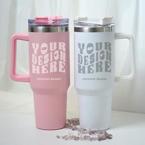 May include: Two insulated tumblers, one pink and one white, with handles and clear straws. Each tumbler has the text "YOUR DESIGN HERE" printed on the front. The pink tumbler has a pink handle and lid, while the white tumbler has a white handle and lid.
