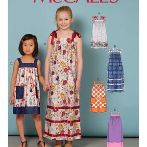 May include: McCall's sewing pattern M7768 featuring girls' dresses. The pattern includes various dress styles with different prints and designs. The dresses have features like bows, floral patterns, and contrasting trim. The McCall's logo is at the top.