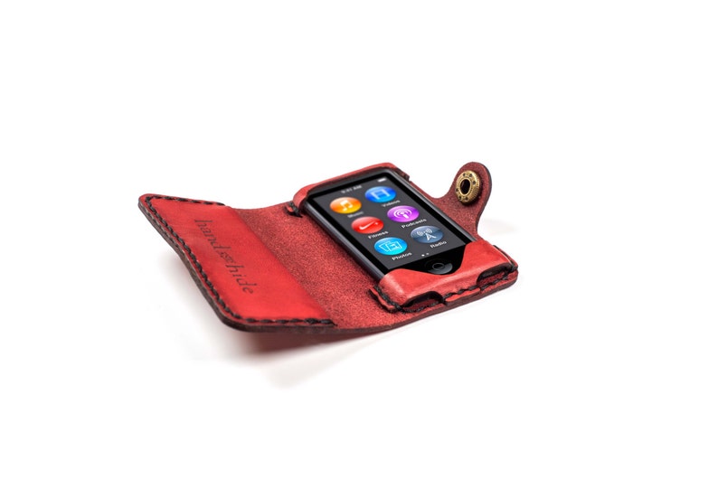May include: Red leather case with a snap closure for an iPod. The case has the words "Handschilde" embossed on the front.