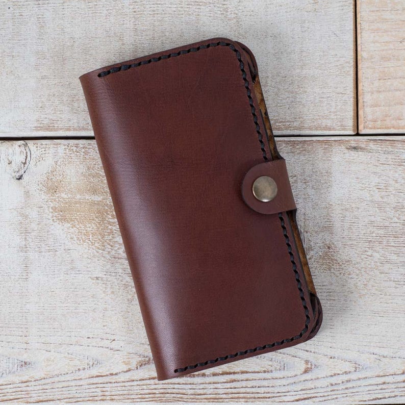 May include: A brown leather wallet with a snap closure and a stitched edge.