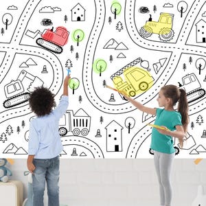 Könnte beinhalten: Ein großes Schwarz-Weiß-Malposter mit einem Straßenkarten-Design mit Baufahrzeugen, Bäumen, Häusern und Wolken. Zwei Kinder malen das Poster mit Pinseln und Farbe aus.