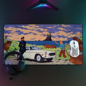 May include: A rectangular mousepad featuring a comic book scene with characters, a white car, and a coastal landscape. The mousepad has a black border and is surrounded by a gaming setup, including a headset and a white mouse.