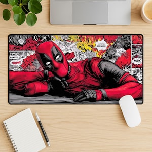 May include: A rectangular mousepad featuring a comic book style illustration of Deadpool in his signature red and black suit. The background is a collage of comic book panels with speech bubbles and action words.