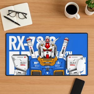 Może przedstawiać: Niebieska prostokątna podkładka pod biurko z szczegółową ilustracją robota Gundam. Robot jest głównie niebieski, biały, czerwony i żółty, z tekstem "RX-78-2" i "EARTH". Biała mysz komputerowa znajduje się po prawej stronie.