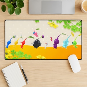 May include: A rectangular mouse mat with a vibrant illustration of Pikmin characters. The design showcases various Pikmin in different colours, set against a yellow and cream backdrop with floral and clover accents. The mat is framed by a black border.