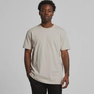 May include: A beige crew neck t-shirt. The short-sleeved shirt is a solid color and appears to be made of a soft material. The person in the image is wearing black pants.