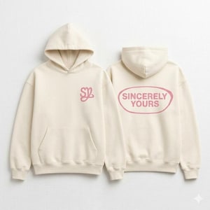 May include: Two cream-colored hoodies with attached hoods. One hoodie has a pink "SZ" logo on the chest. The other hoodie has the words "Sincerely Yours" in a pink oval on the back. Both hoodies have a front pocket.