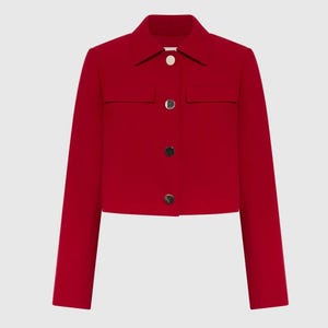Puede incluir: Chaqueta corta roja brillante con cuello y mangas largas. Tiene dos pequeños bolsillos en el pecho y se abrocha con tres botones dorados. La tela es de color liso y suave, adecuada para diversas ocasiones.