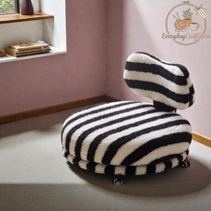 Op de afbeelding: Een moderne, lage stoel met een zwart-wit zebra streepmotief. De stoel heeft een ronde zitting en een gebogen rugleuning. De stoel is gemaakt van een zachte, getextureerde stof en heeft kleine, zilverkleurige voetjes.
