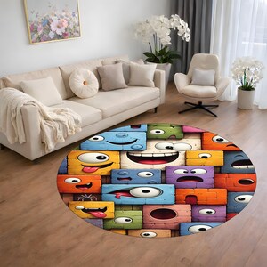 May include: A colorful, round area rug featuring a cartoon design of expressive, rectangular faces with various emotions. The rug's design incorporates blue, orange, yellow, green, and purple blocks, creating a playful and whimsical aesthetic.