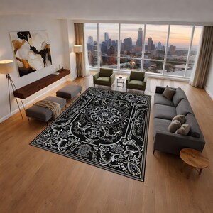Peut inclure: Un grand tapis noir avec un motif floral blanc et gris orné. Le tapis présente un médaillon central et une bordure détaillée. Le tapis est placé dans un salon moderne avec vue sur la ville.