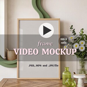 Puede incluir: Una maqueta de marco de fotos de madera clara con un icono de botón de reproducción y el texto frame VIDEO MOCKUP, DIN A ratio, .PSD, .MP4 and .JPG file, y MODERA Mockups. El marco se muestra sobre una superficie de madera con decoración de cristal verde y flores.