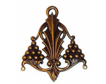 May include: A bronze-toned metal pendant featuring a central vertical spear-like element flanked by two triangular clusters of small spheres. The piece has an ornate, symmetrical design with a top loop for hanging and two small side loops at the base.