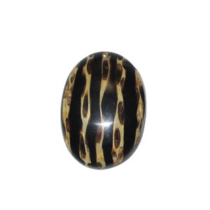May include: A round, black and gold pendant with a striped pattern. The pendant is made of a natural material, possibly wood or bone.
