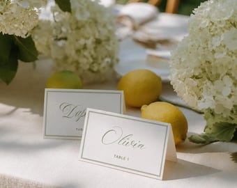Tarjeta de mesa con caligrafía verde salvia, etiquetas de nombres de asientos editables, papelería elegante para jardín, descarga en Canva.