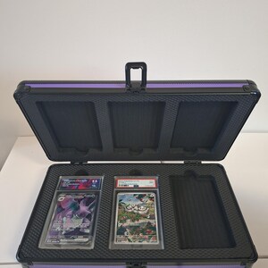 Puede incluir: Malet&iacute;n negro abierto para tarjetas con ribete morado, que contiene dos cartas coleccionables calificadas. El malet&iacute;n tiene un asa e inserciones de espuma para asegurar las tarjetas.