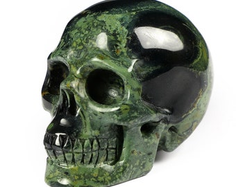 May include: A green and black skull carved from a stone with a mottled pattern. The skull is detailed with a defined jawline and teeth.