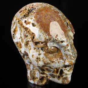May include: A carved agate stone sculpture of a face with a white and brown colour scheme. The stone has a rough, textured surface.