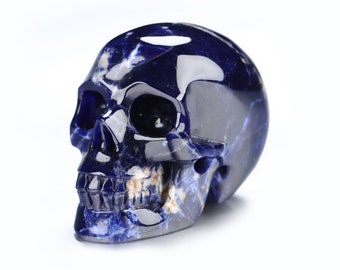 Puede incluir: Un cráneo tallado en sodalita, una piedra preciosa azul oscuro, con detalles azules y blancos.