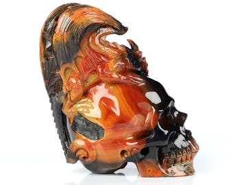 May include: A carved skull made of agate with a dragon design on top. The skull is black and the dragon is orange, yellow, and black.