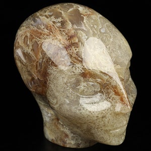Puede incluir: Una escultura tallada en ágata de una cabeza humana con intrincados patrones y remolinos de marrón y blanco.