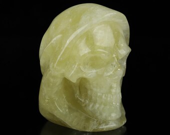 May include: A yellow crystal skull sculpture. The skull is carved in detail and has a smooth, polished finish.