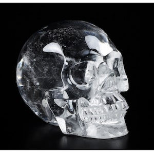 Op de afbeelding: Een transparante kwartskristallen schedelsculptuur. De schedel is gedetailleerd gesneden, met zichtbare oogkassen, een neus en tanden.