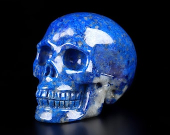 Op de afbeelding: Een blauwe en witte gesneden lapis lazuli schedel. De schedel is gedetailleerd met oogkassen, een neus en tanden.