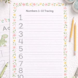 May include: A white tracing worksheet with the text "Numbers 1-10 Tracing" and floral border. The numbers 1 to 10 are printed in a traceable font. Two yellow pencils, a pair of green scissors, and other school supplies are also visible.