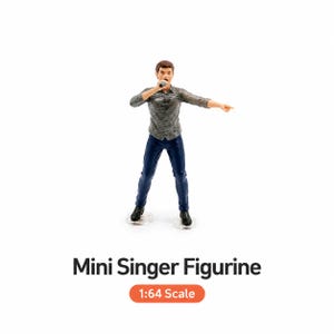 May include: A small figurine of a male singer wearing a grey patterned shirt and blue trousers, holding a microphone and pointing. The figurine is on a clear base. Text on the image reads "Mini Singer Figurine" and "1:64 Scale".