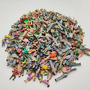 May include: A large collection of miniature plastic human figures in various poses and colors, including red, blue, green, yellow, and grey. The small figurines are scattered in a dense pile, showing diverse clothing styles and standing positions.