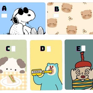 K&ouml;nnte beinhalten: Eine Sammlung von f&uuml;nf farbenfrohen Kartendesigns. Eines zeigt Snoopy mit Sonnenbrille, ein anderes wiederholt B&auml;rengesichter, und ein drittes zeigt einen Hund mit einem Sandwich. Das vierte Design zeigt einen B&auml;ren, der "ENERGY" trinkt, und das letzte einen Cartoon-Charakter.