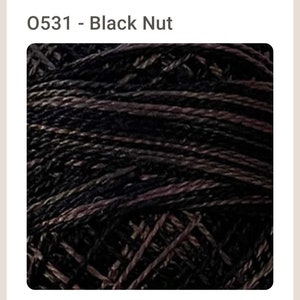 May include: Close-up of a skein of black and purple yarn. The yarn is textured and has a subtle sheen.