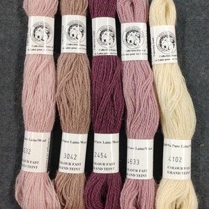 May include: Five skeins of pure wool yarn in shades of pink, beige, burgundy, and cream. The yarn is labeled with the brand name "Fine Dauphinois" and the color numbers 632, 3042, 2454, 4633, and 4102. The yarn is labeled as "Colour Fast" and "Grand Teint".