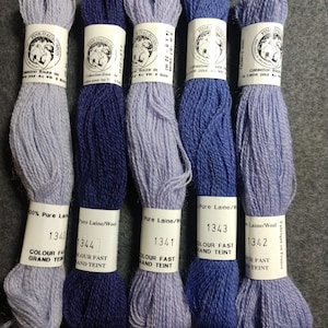 May include: Six skeins of 100% pure wool yarn in various shades of blue and purple. The yarn is labeled with the brand name "Fine Dauphinois", the color number, and the words "Colour Fast Grand Teint".