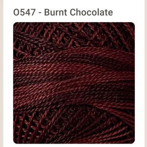 May include: A close-up of a ball of dark red yarn with a subtle gradient of color. The yarn is made of a soft, textured material and is perfect for knitting or crocheting.