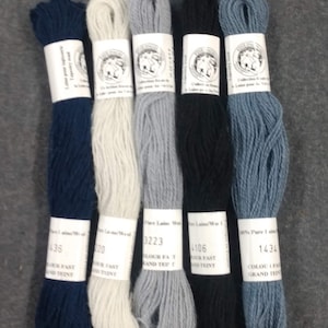 May include: Six skeins of tapestry wool in various colors: navy, off-white, light grey, black, and denim blue. Each skein is labeled with a color number and the words "Pure Laine/Wool". The skeins are arranged vertically against a grey background.