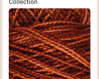 May include: Close-up of a spool of rust-colored embroidery floss. The floss is tightly wound and has a slightly textured surface.