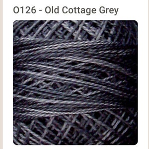 May include: Close-up of a skein of dark gray embroidery floss. The floss is tightly wound and has a slightly textured surface.