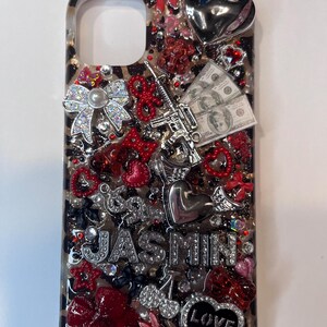 Pu&ograve; includere: Custodia decorativa per telefono con sfondo a stampa leopardata. Gli abbellimenti includono strass, fiocchi, cuori, una pistola giocattolo e una piccola pila di banconote. Il nome "JASMIN" &egrave; scritto con strass e un ciondolo a forma di cuore recita "LOVE".