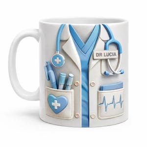 Puede incluir: Taza de cerámica blanca con un diseño de bata de médico en blanco y azul. El diseño incluye un estetoscopio, bolígrafos y el nombre "DR LUCIA". También es visible un bolsillo en forma de corazón con una cruz.
