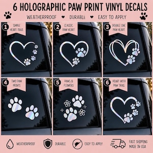 Op de afbeelding: Zes holografische vinylstickers met pootafdruk- en hartontwerpen. De set bevat een hart met pootjespad, klassiek poothart, dubbellijns poothart, twee pootafdrukken, pootjes met bloemen en een hart met een pootjespad, getoond op autoruiten.