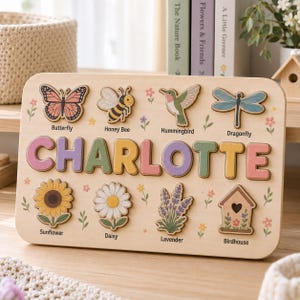 May include: A rectangular wooden name puzzle featuring the name CHARLOTTE in large, colorful letters. The board includes eight cut-out shapes of a butterfly, honey bee, hummingbird, dragonfly, sunflower, daisy, lavender, and birdhouse with labels.
