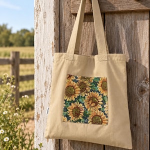 May include: A beige canvas tote bag featuring a rectangular patch on the front with a detailed woven sunflower pattern. The bag has two shoulder straps and a small white label on the side seam with the text Pourlod printed in black.