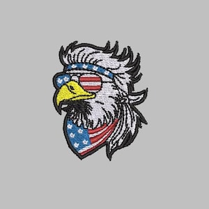 Op de afbeelding: Geborduurde patch met een adelaarskop met zonnebril en hoofdband, beide versierd met de Amerikaanse vlag. De adelaar heeft een gele snavel en een zwarte baard, tegen een grijze achtergrond.