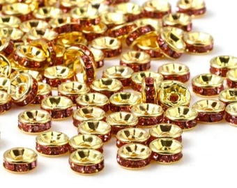 May include: A large quantity of gold-colored metal bead caps with a single row of small, dark red rhinestones around the edge.