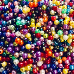 May include: A large assortment of colorful plastic beads in various shades of red, blue, green, yellow, purple, and white. The beads are round and have a smooth, glossy finish.
