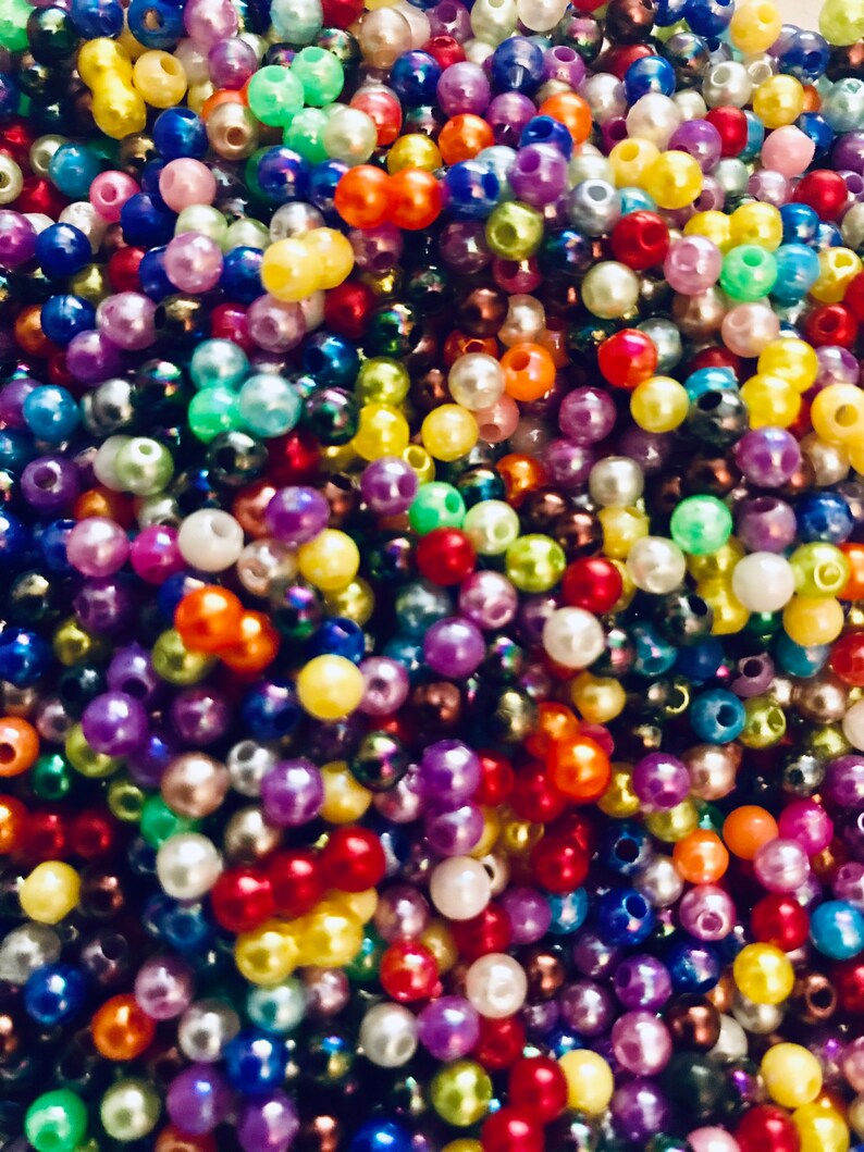 May include: A large assortment of colorful plastic beads in various shades of red, blue, green, yellow, purple, and white. The beads are round and have a smooth, glossy finish.