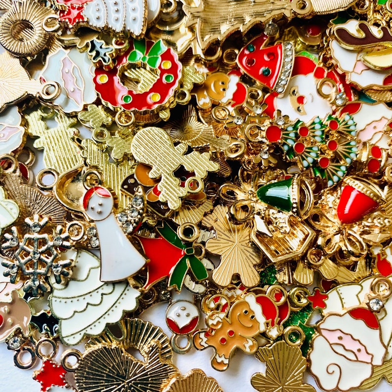 May include: Assortment of gold-tone Christmas charms with various designs, including snowflakes, bells, wreaths, and gingerbread men. The charms are decorated with red, green, white, and gold enamel.