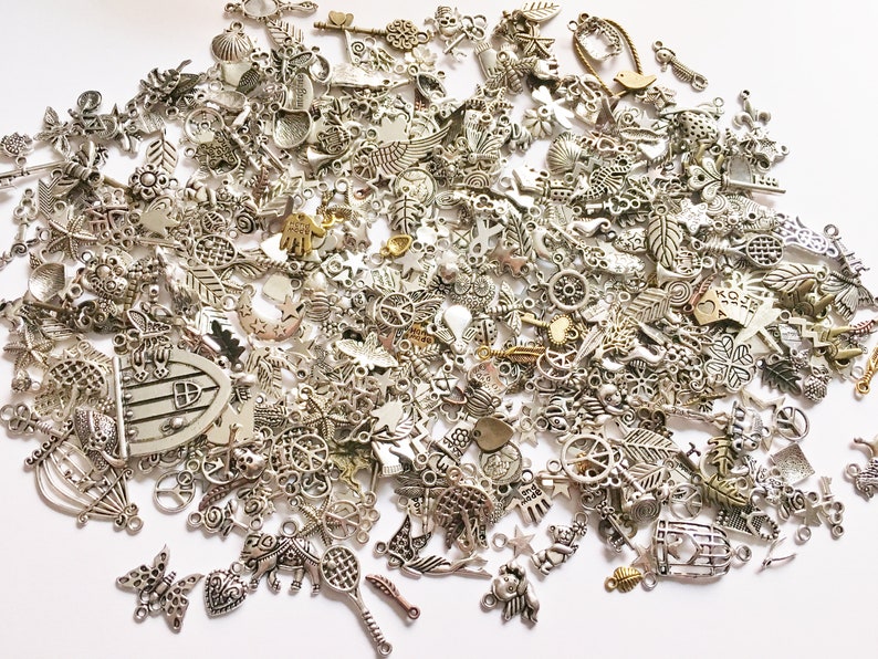 Puede incluir: Un gran surtido de colgantes de amuleto de plata con varios dise&ntilde;os, incluyendo corazones, estrellas, hojas y mucho m&aacute;s. Estos colgantes son perfectos para agregar un toque personal a los proyectos de joyer&iacute;a.